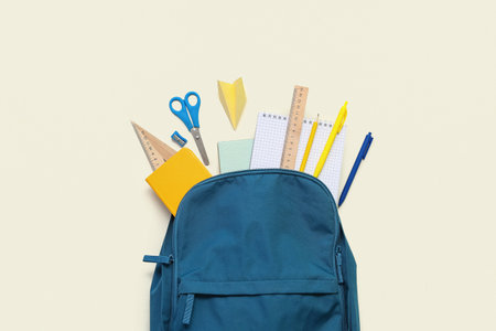 School backpack with paper plane and different stationery on light backgroundの写真素材