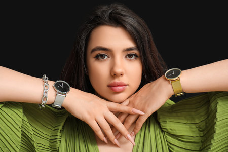 Beautiful young woman with wrist watches on black backgroundの写真素材