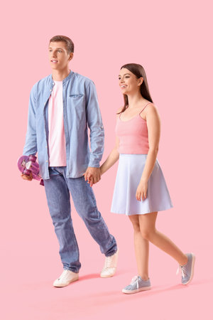 Happy young couple with skateboard on pink backgroundの写真素材