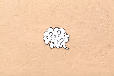Speech bubble with question marks on beige backgroundの写真素材