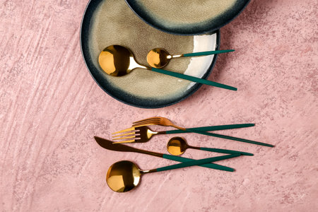 Clean plates and set of golden cutlery on dark pink tableの写真素材