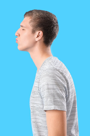 Young man blowing kiss on blue backgroundの写真素材