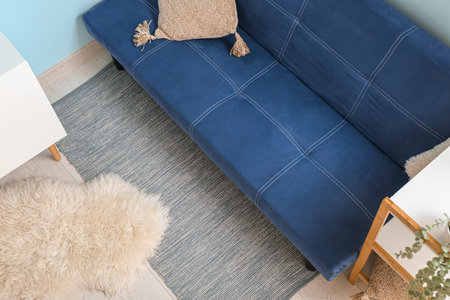Stylish interior of living room with sofa, shelving unit and soft rugs