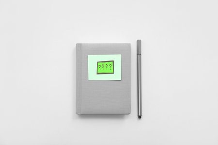Notebook with paper quiz card and pen on white background