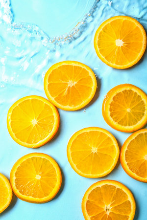 Slices of fresh orange in water on blue background