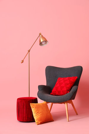 Black armchair with pouf and lamp on pink backgroundの写真素材