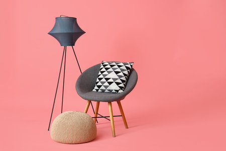 Gray armchair with pouf and lamp on pink backgroundの写真素材