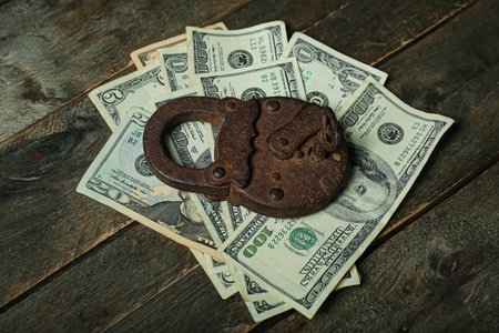 Lock with dollar banknotes on dark wooden background. Sanctions conceptの写真素材