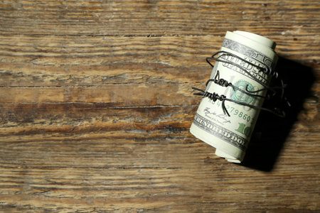 Dollar banknotes with barbed wire on wooden background. Sanctions conceptの写真素材
