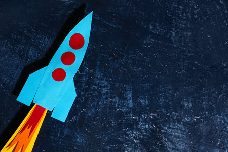 Blue paper rocket on dark grunge backgroundの写真素材