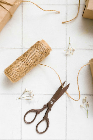 Tied boxes with scissors, thread and dried twigs on white tile backgroundの写真素材