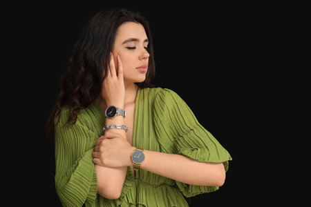 Beautiful young woman with wrist watches on black backgroundの写真素材