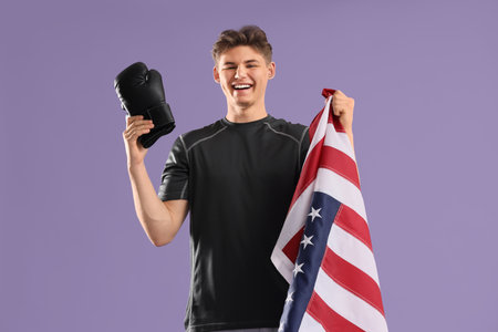 Male boxer with USA flag and boxing gloves on lilac backgroundの写真素材