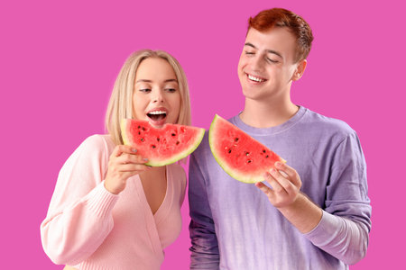Young beautiful man and woman with slices of fresh watermelon on purple backgroundの写真素材