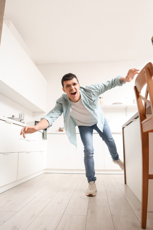 Young man tripping over table in kitchen. Trauma conceptの写真素材