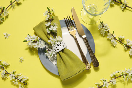 Beautiful table setting with blossoming branches on yellow backgroundの写真素材