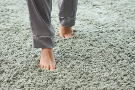 Barefoot woman walking on green carpet at home, closeupの写真素材