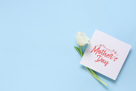 Greeting card with text HAPPY MOTHER'S DAY and beautiful white tulip on blue backgroundの写真素材