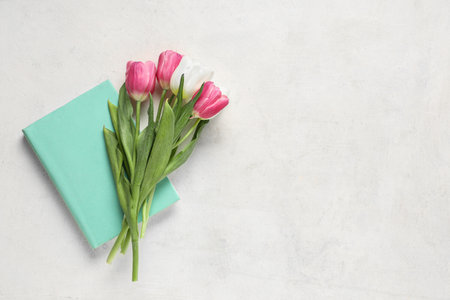 Notebook with beautiful tulips on white background. Mother's Day celebrationの写真素材