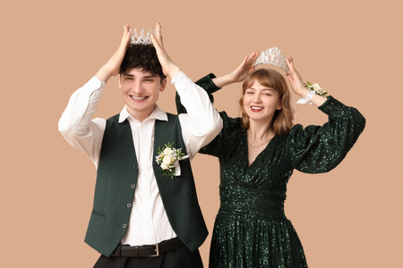 Happy prom couple with crowns on beige backgroundの写真素材
