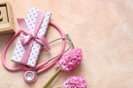 Stethoscope with gift box and flowers for International Nurses Day on beige grunge backgroundの写真素材