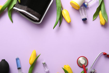 Sphygmomanometer with stethoscope, ampules and yellow tulips for International Nurses Day on lilac backgroundの写真素材