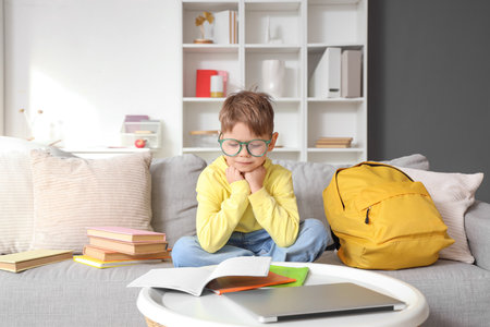 Cute little boy in eyeglasses doing homework at homeの写真素材