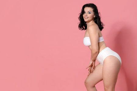 Beautiful young happy body positive woman in stylish underwear on pink backgroundの写真素材