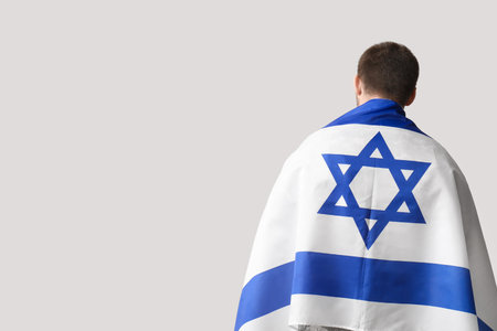 Male Jewish soldier with flag of Israel on light background, back viewの写真素材