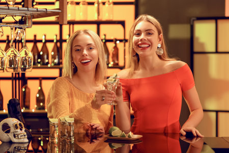 Young women with tequila shots in bar at nightの写真素材