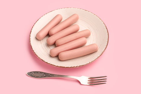 Plate with tasty thin sausages on pink backgroundの写真素材