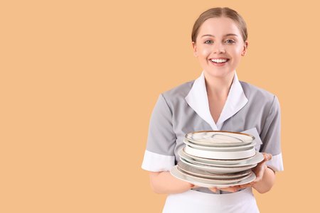 Young waitress with many plates on beige backgroundの写真素材