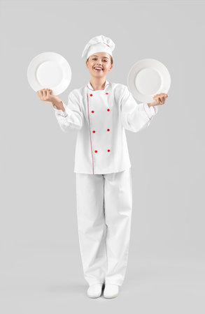 Female chef with empty plates on gray backgroundの写真素材