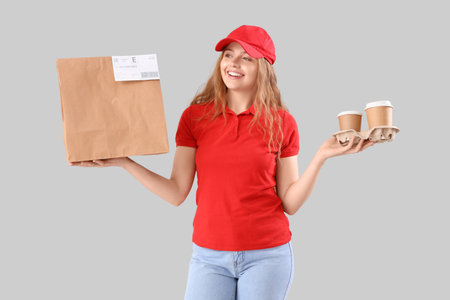 Female courier with food on gray backgroundの写真素材
