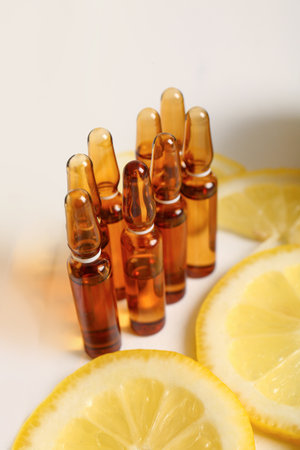 Ampoules with vitamin C and lemon slices on white backgroundの写真素材