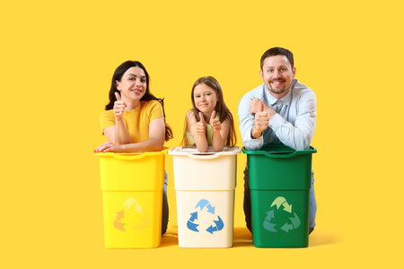Family with recycle bins on yellow backgroundの写真素材