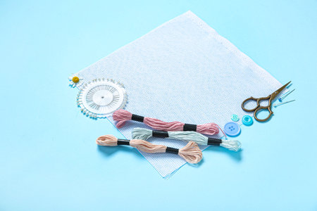 Canvas with scissors, mouline threads and ball pins on blue backgroundの写真素材