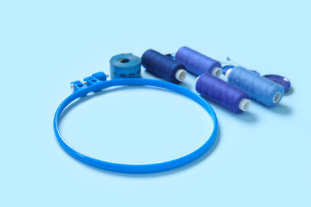 Embroidery hoop with thread spools, buttons and measuring tape on blue backgroundの写真素材