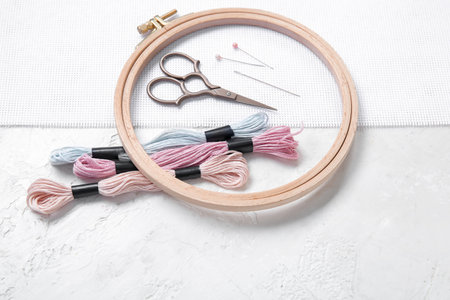 Wooden embroidery hoop with scissors, mouline threads and canvas on grunge white backgroundの写真素材