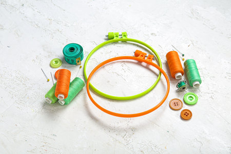 Embroidery hoops with thread spools, buttons and measuring tape on grunge white backgroundの写真素材