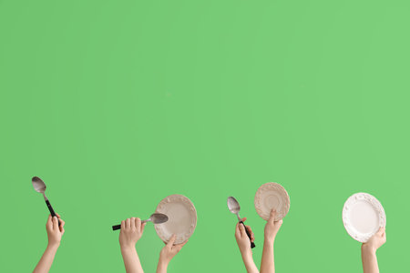 Women with plates and spoons on green background
