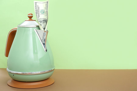 Electric kettle with dollar banknote on table near green wallの写真素材