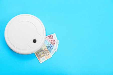Robot vacuum cleaner with euro banknotes on blue backgroundの写真素材