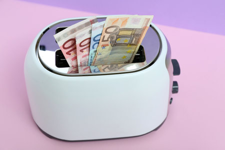 Toaster with euro banknotes on table near lilac wallの写真素材