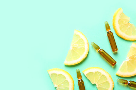 Ampoules with vitamin C and lemon slices on turquoise backgroundの写真素材