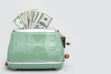 Toaster with dollar banknotes on light background