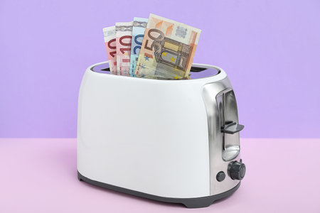 Toaster with euro banknotes on table near lilac wallの写真素材