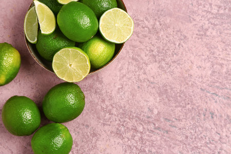 Bowl with fresh limes on purple background