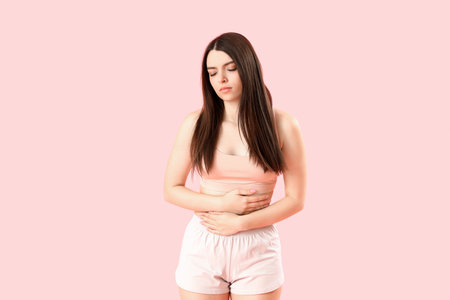 Young woman having menstrual cramps on pink backgroundの写真素材
