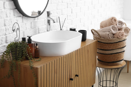 Houseplant, bath accessories and sink bowl on wooden cabinet in bathroomの写真素材